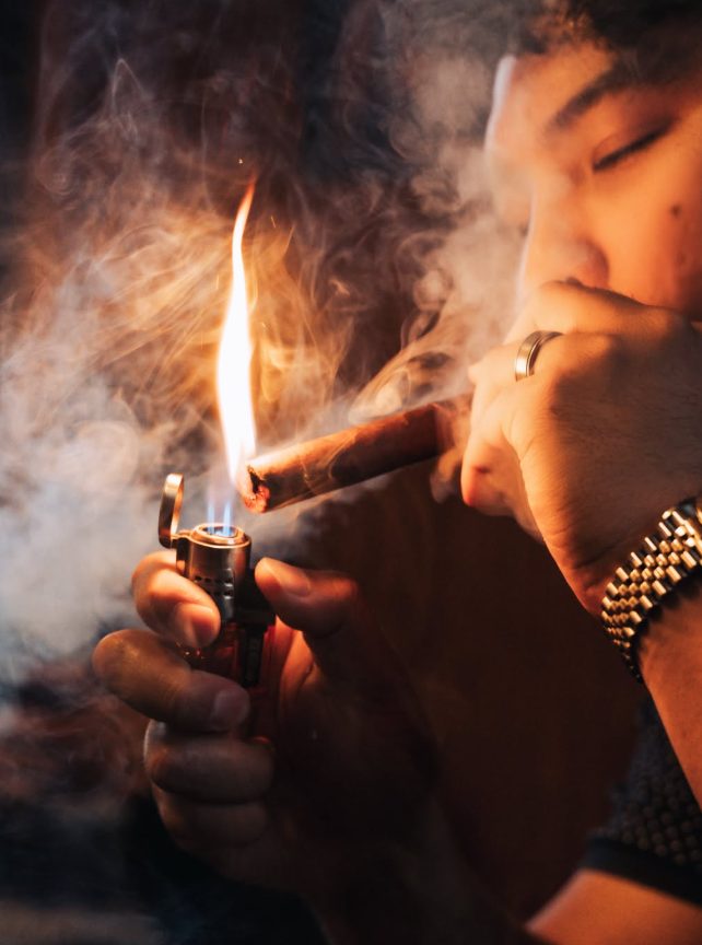 Close-up of a cigar being lit, flame and smoke
